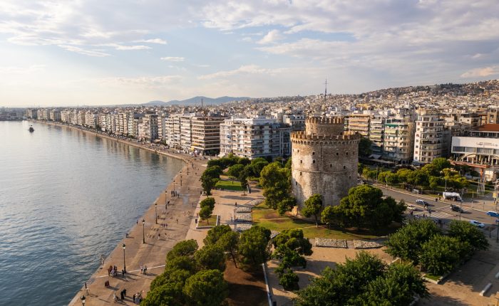 Aerial view of the White Tower in Thessaloniki, Greece, surrounded by lush greenery and the vibrant
